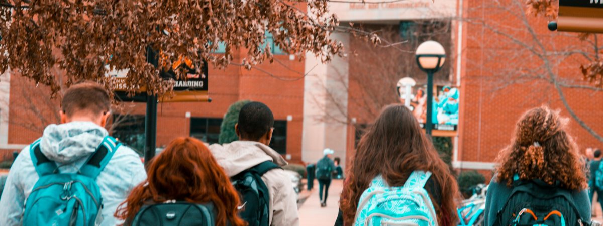 A group of college students with backpacks walking together outdoors on campus.